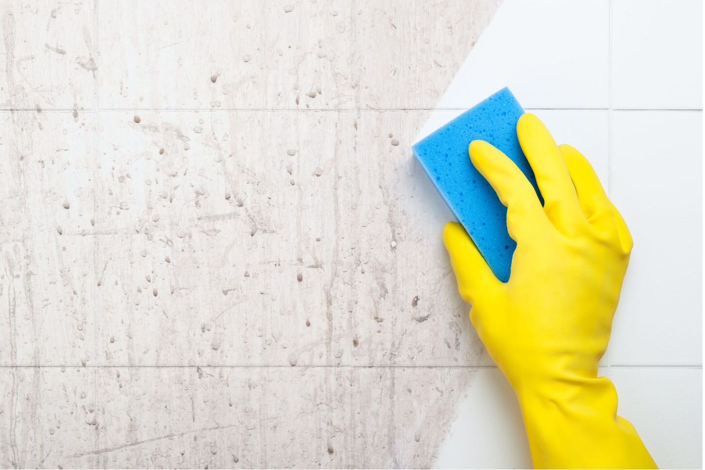 Gloved hand deep cleaning a tiled surface with a blue sponge
