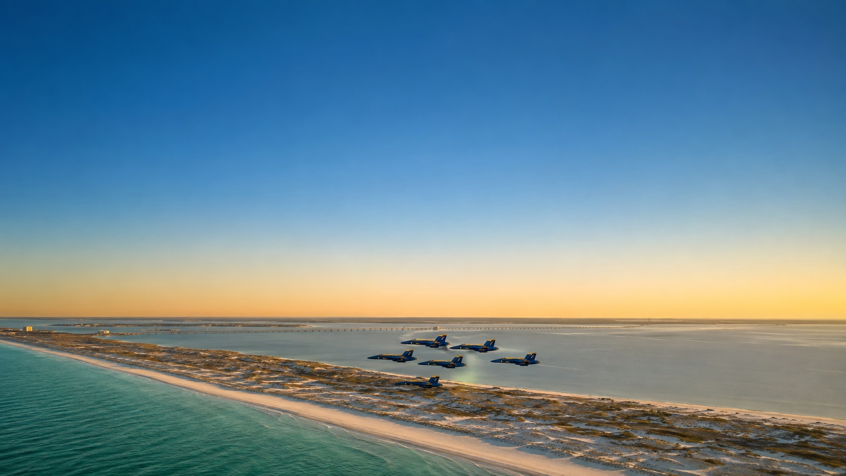 Aerial sunset view of the Pensacola coastline with the Blue Angels flying above the water